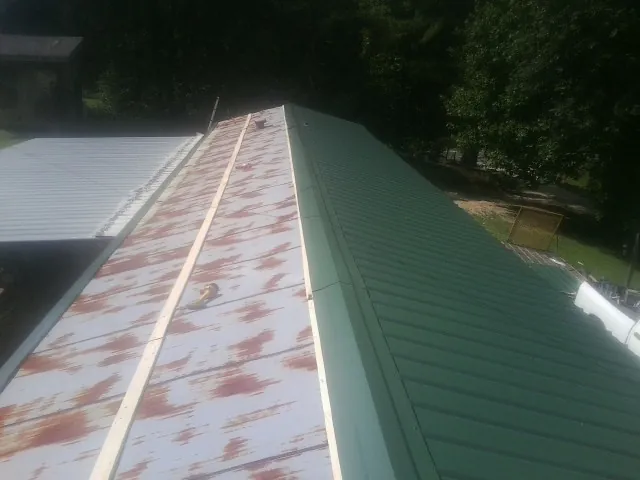 Old rusted panels beside newly installed green metal roofing — Wind Damage Roof Repair by Roofing Brothers in Trumansburg