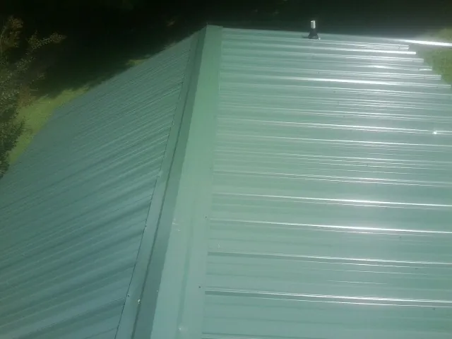 New green metal panels meeting at the ridge of a roof — Flat Roof Repair work by our crew in Trumansburg
